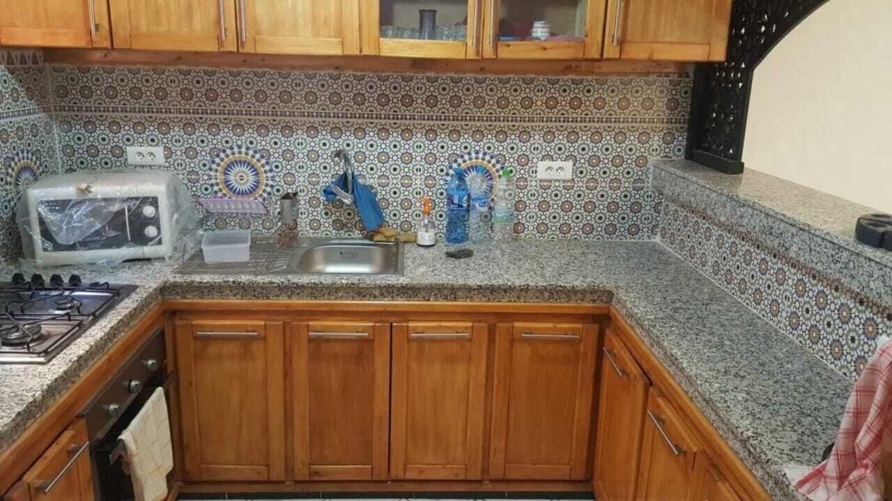 A kitchen with wooden cabinets, a tiled backsplash, a sink, a stove, and a toaster.