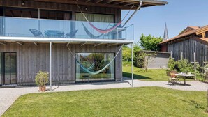 Een modern herenhuis met een glazen balkon, een hangmat en een klein terras.