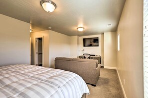 A bedroom with a bed, a sofa, a television, and a door leading to a bathroom.