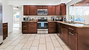 Una cocina moderna con armarios de madera oscura, electrodomésticos de acero inoxidable y encimera de granito.