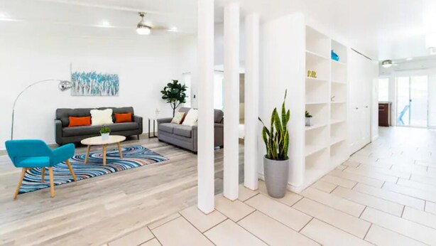 Una sala de estar moderna con un sofá, sillones, una mesa de centro y una planta en maceta.