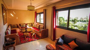 A living room with a sofa set, a coffee table, and a chandelier. - Quiet stay - MARRAKECH : Apartment 87 m² SWIMMING POOL, FREE WIFI, PARKING (Marrakech)