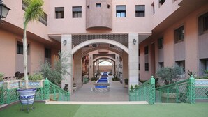 A hotel courtyard with a central pathway, green railings, and potted plants. - Quiet stay - MARRAKECH : Apartment 87 m² SWIMMING POOL, FREE WIFI, PARKING (Marrakech)