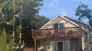 A two-story house with a balcony, a deck, and a covered outdoor seating area.