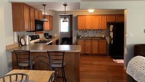 A kitchen with wooden cabinets, a central island with bar stools, a microwave, stove, and a refrigerator.