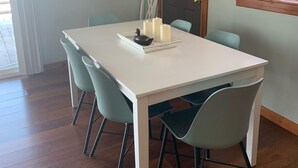 A dining area with a white table, teal chairs, and a modern chandelier.