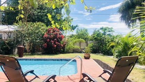 A swimming pool with two lounge chairs. - Charming Bungalow, remodeled, heated pool, walk to the beach (Naples)