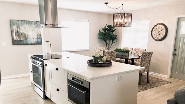 A modern kitchen with white cabinetry, a stainless steel range hood, and a built-in oven. - Charming Bungalow, remodeled, heated pool, walk to the beach (Naples)