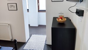 Ein Zimmer mit einem schwarzen Schreibtisch, einer Obstschale und gerahmten Bildern an der Wand.