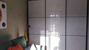 Een kamer met een groene bank, een witte tafel met een vaas en een groot raam dat een gebouw weerspiegelt.