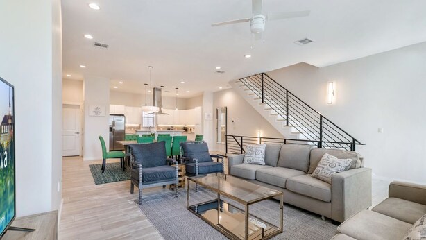 Un salon moderne avec un canapé, une table basse et des fauteuils. Un escalier m ène à un niveau supérieur.