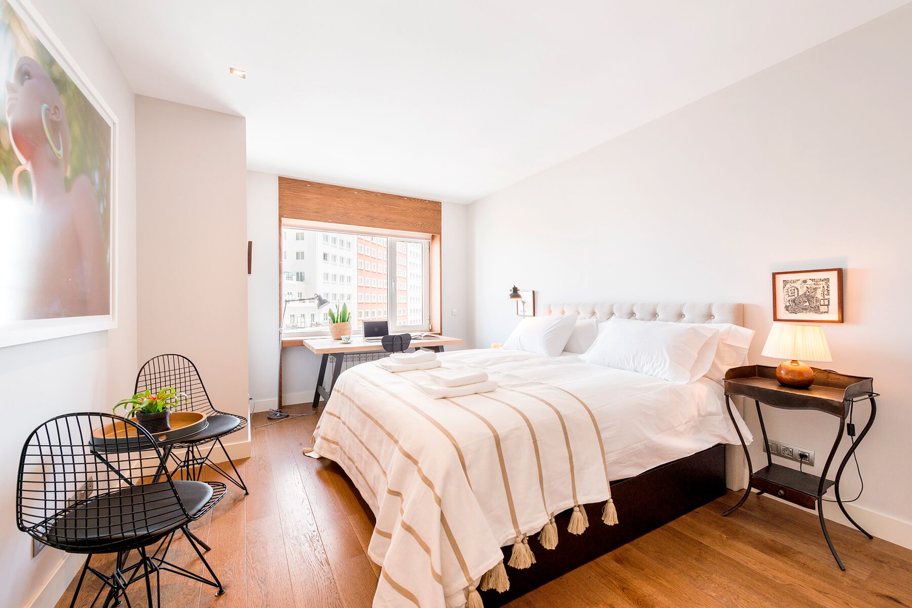 A modern bedroom with a large bed, a desk, and a chair.