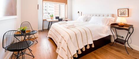 A modern bedroom with a large bed, a desk, and a chair.