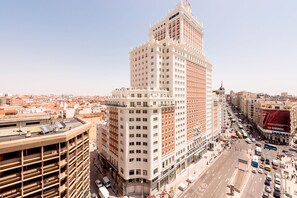Un grand hôtel à plusieurs étages, avec une tour imposante située à l’angle et une rue animée en contrebas.