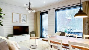 Una sala de estar moderna con televisor, sofá y mesa de comedor.
