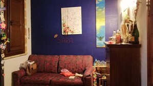 A room with a blue wall, a sofa, a map, and a decorative shelf.