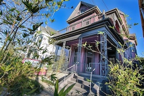 A two-story house with a porch and a staircase leading to the entrance. - Claiborne Victorian Mansion, by Historic Getaways (New Orleans)
