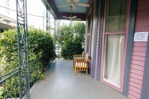 A covered porch with a ceiling fan, a wooden bench, and a metal railing. - Claiborne Victorian Mansion, by Historic Getaways (New Orleans)