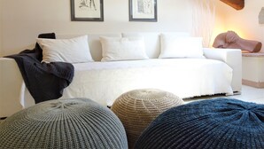 A modern bedroom with a white sofa, two framed artworks, a wooden ceiling beam, and a large window. - Casa Clelia: the gem in the heart of the Langhe (Loazzolo)