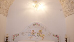 A room with a stone arch ceiling, a bed with a floral headboard, and bedside lamps.
