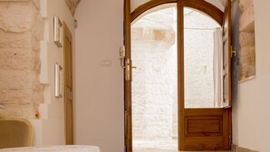 A room with a stone wall, a wooden door, and a table with a white tablecloth.