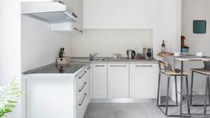 A modern kitchen with a built-in stove, a sink, and a dining area with two stools. - Cute Studio in Old Town (Como)