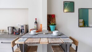 A dining area with a wooden table, two chairs, a coffee machine, a kettle, and a potted plant. - Cute Studio in Old Town (Como)