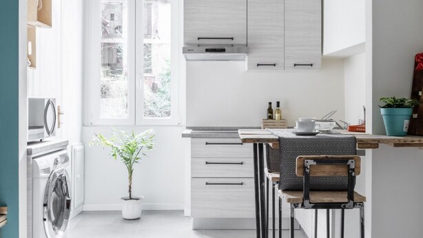 A modern kitchen with white cabinetry, a built-in oven, and a window providing natural light. - Cute Studio in Old Town (Como)