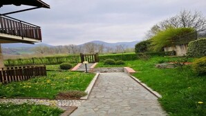 A stone pathway leading to a wooden gate, surrounded by lush greenery and a view of distant mountains. - STELLA DELLE GRIGNE (Pasturo)