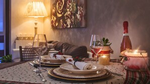 A dining table set with plates, glasses, and cutlery, a candle, and a bottle of wine. - STELLA DELLE GRIGNE (Pasturo)