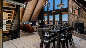 A dining area with a high ceiling, stone walls, and a view of the outdoors.
