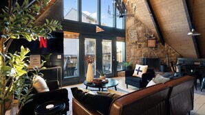 A cozy living room with a stone wall, a fireplace, and a large window.