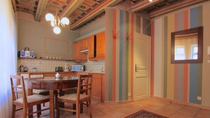 Uma cozinha com armários de madeira, painel de azulejos, micro-ondas e uma área de refeições com cadeiras e mesa.