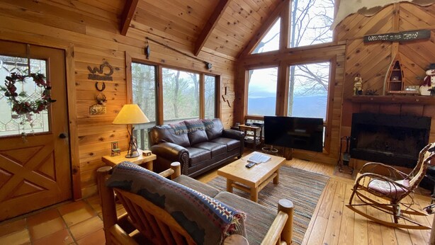 A cozy cabin interior with a leather sofa, wooden coffee table, and a fireplace. - Pet-Friendly,Cozy Cabin,Hot Tub,Wood Fireplace,WiFi (Ferguson)