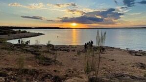 A sunset over a calm lake with rocky shores and sparse vegetation. - Blissful RV Retreat in Canyon Lake! Only 5 minutes from the lake and river! (Canyon Lake)