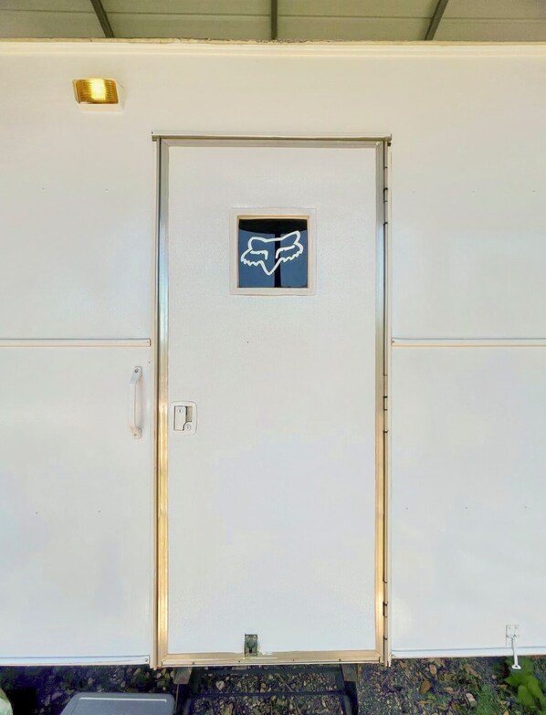 A white utility door with a logo, a handle, and a small window.