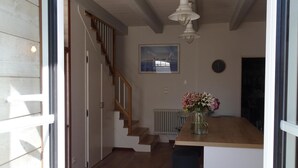 Una cucina con isola in legno, zona pranzo con una sedia blu, una scala e una ventola a soffitto.