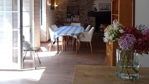 Un'area pranzo con tovaglia a quadri, sedie di legno e un vaso di fiori su un tavolo in legno.