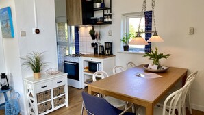 Cocina compacta con estufa, microondas y plantas colgantes.