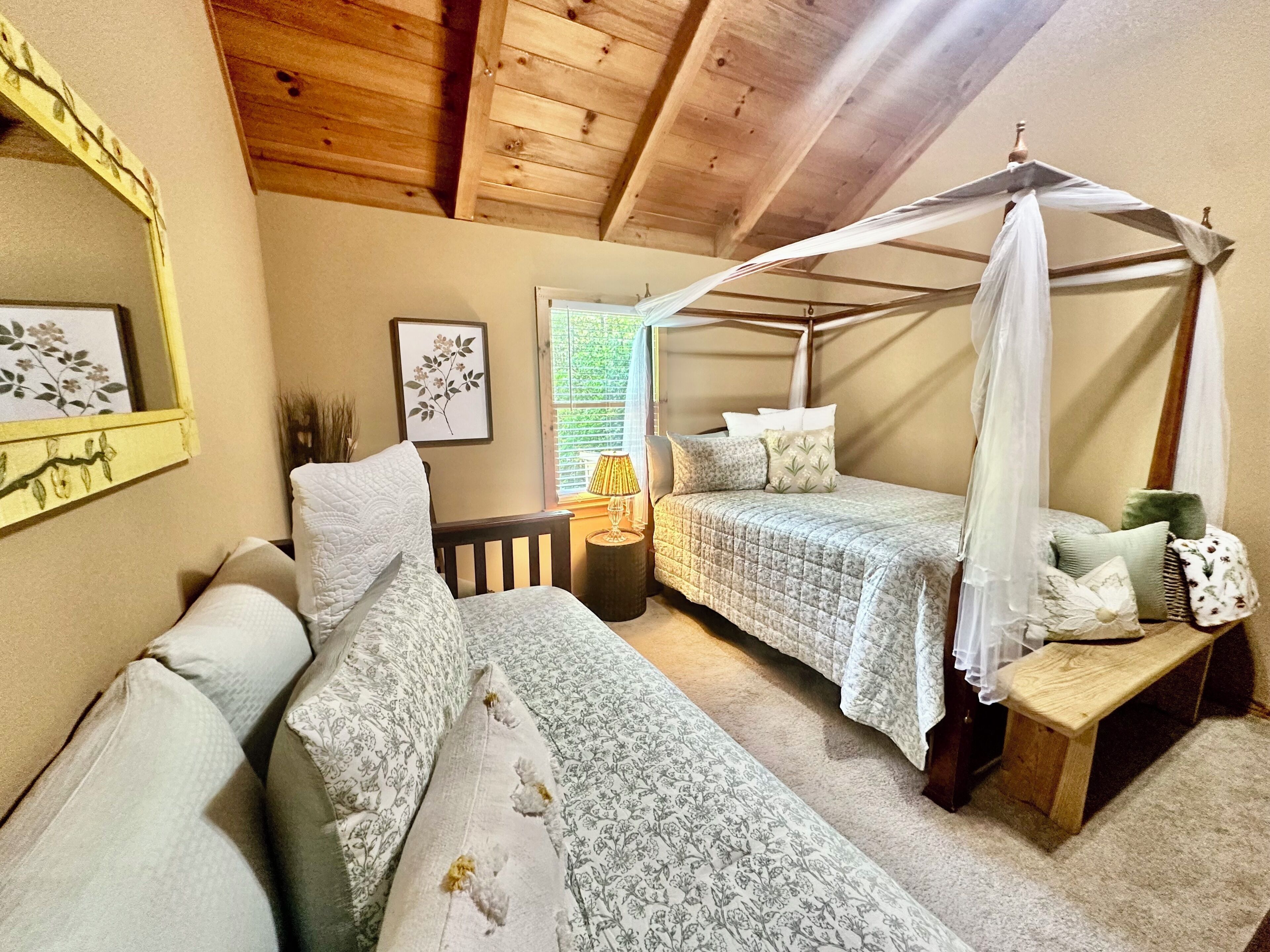 A bedroom with a canopy bed, a sofa, a bench, and a bedside table.