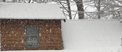 A wooden cabin with a snow-covered roof and a porch.