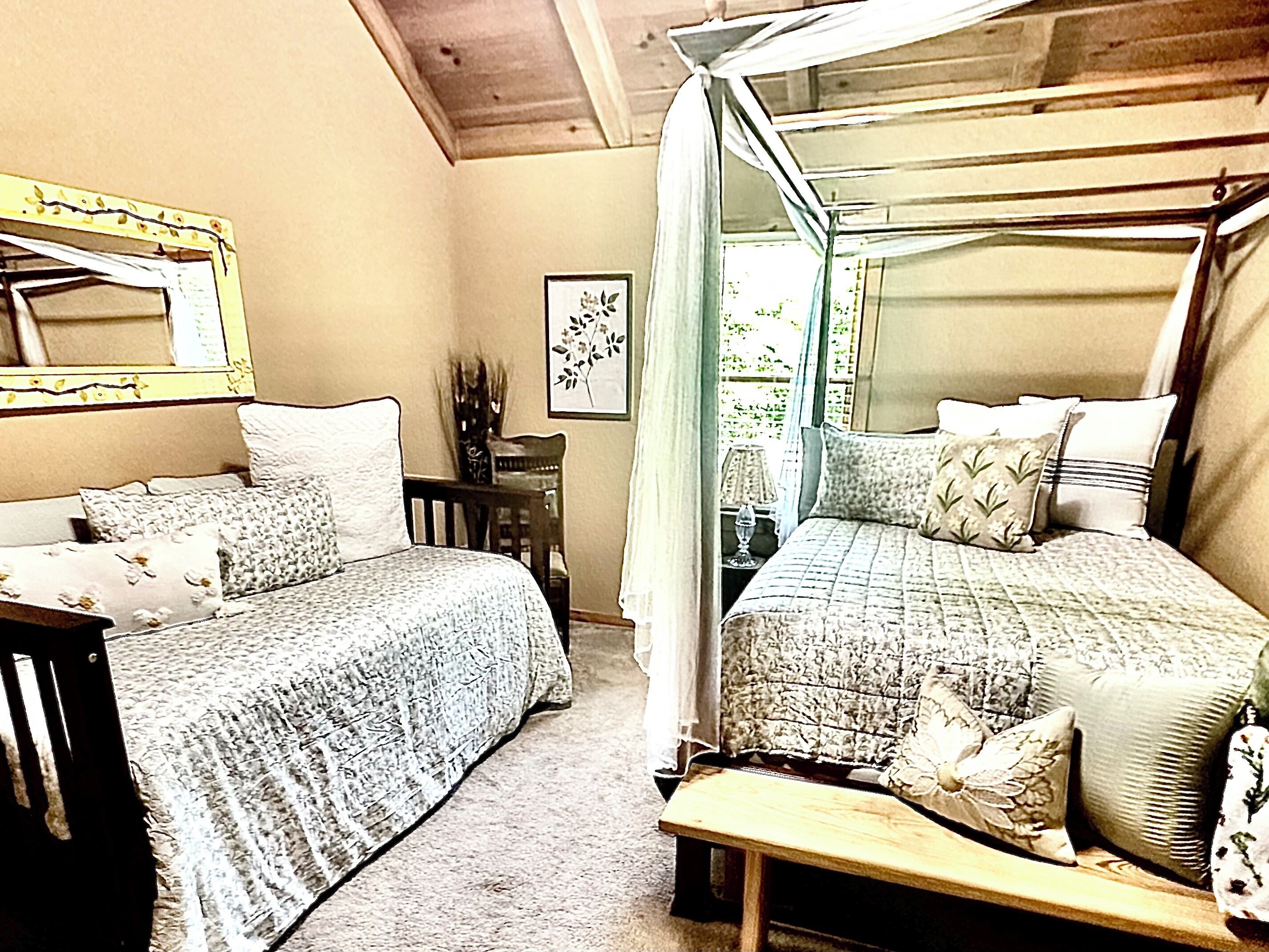 A bedroom with two beds, a wooden bench, a chair, a mirror, and a framed picture on the wall.