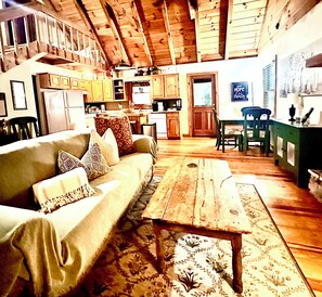 A cozy living room with a sofa, a coffee table, and a dining area with a table and chairs.