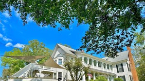 A large, two-story house with a covered porch and a brick chimney. - Getaway at "The Magnolia Suite" Pool, Hot tub, fire pit, kayaks, & lake access! (Cedar Bluff)