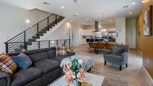 A modern living room with a sofa, armchair, and a staircase leading to an upper floor.