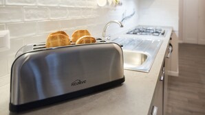 Une cuisine avec un grille-pain sur le comptoir, un évier et une cuisinière.