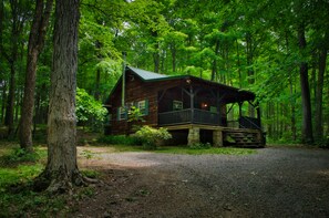 A cabin with a porch, surrounded by dense forest.
