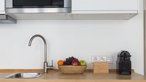 A kitchen with a stainless steel sink, a fruit bowl on the counter, a coffee maker, and a power strip. - The Tin Artist Atelier 1 bedroom apartment (Lisboa)