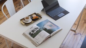 A white table with a laptop, a magazine, and a tray with a cup and pastries. - The Tin Artist Atelier 1 bedroom apartment (Lisboa)