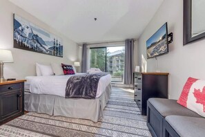 Une chambre d’hôtel avec un lit, un bureau, une chaise, une télévision et une grande fenêtre.